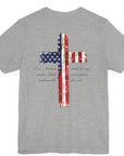 rear view of an athletic heather colored fabric patriotic shirt with americantees.us logo on front and American flag in shape of a Christian cross with pledge of allegiance surrounding image on back