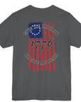 rear view of a asphalt colored fabric shirt with americantees.us logo on front and betsy ross flag with the phrase give me liberty or give me death and 1776 on the back