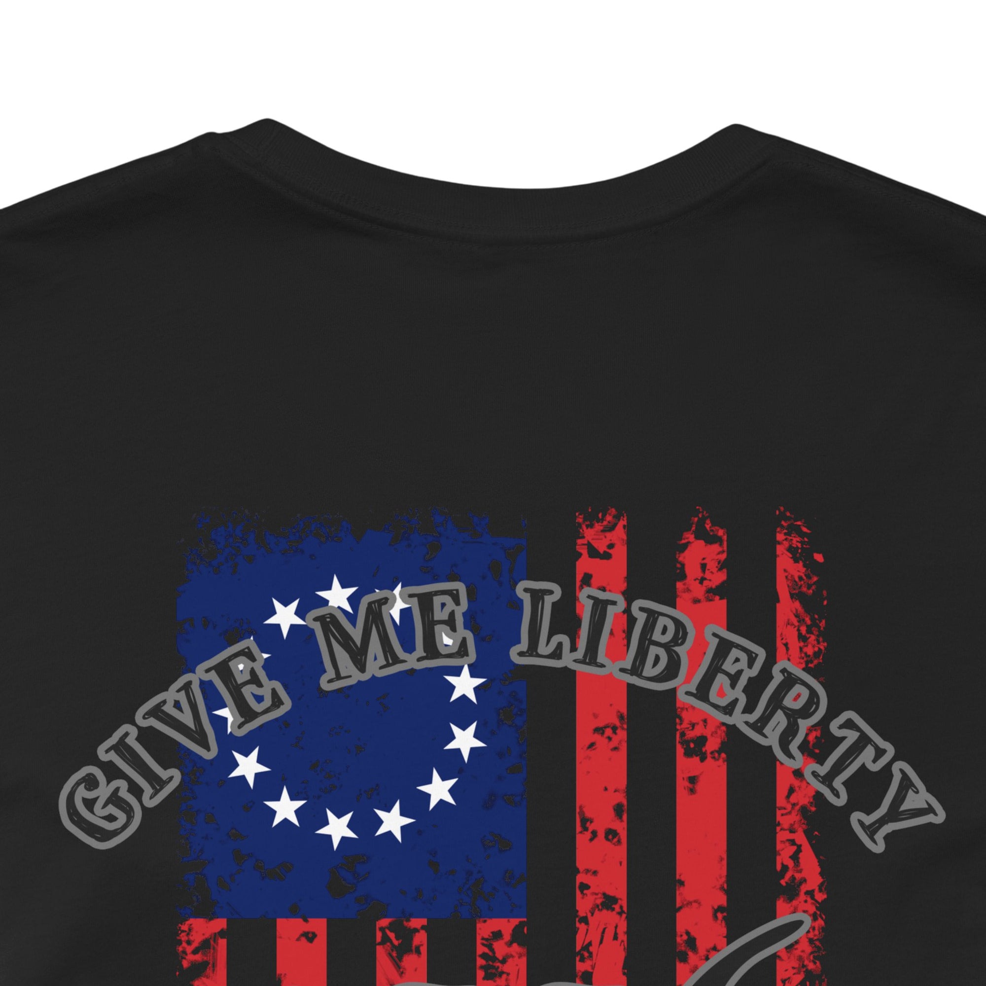 rear view closeup of a black colored fabric shirt with americantees.us logo on front and betsy ross flag with the phrase give me liberty or give me death and 1776 on the back
