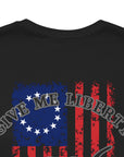 rear view closeup of a black colored fabric shirt with americantees.us logo on front and betsy ross flag with the phrase give me liberty or give me death and 1776 on the back