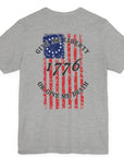 rear view of a athletic heather colored fabric shirt with americantees.us logo on front and betsy ross flag with the phrase give me liberty or give me death and 1776 on the back