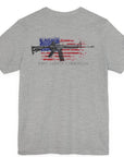Athletic heather color fabric patriotic shirt rear view has an americantees.us logo with eagle head on front , rear view has distressed American flag with modern sporting rifle with the log Pro Armis Libertas meaning For Arms, Freedom