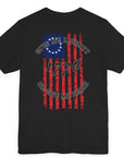 rear view of a black colored fabric shirt with americantees.us logo on front and betsy ross flag with the phrase give me liberty or give me death and 1776 on the back