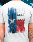 rear view of a man wearing a white colored fabric shirt standing in front of an american flag with americantees.us logo on front and Texas flag with rifle and Keep Texas Free writing on back