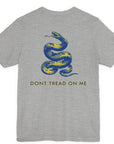 rear view of a athletic heather colored fabric shirt with americantees.us logo on front and a Gadsden flag on the back