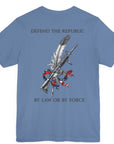 Back view of a lavender blue colored t-shirt with a graphic design of a rifle crossed with a quill fountain pen and an American flag ribbon, with the quote Defend the Republic by law or by force. Patriotic Shirts. logo design on front.