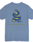 rear view of a steel blue colored fabric shirt with americantees.us logo on front and a Gadsden flag on the back