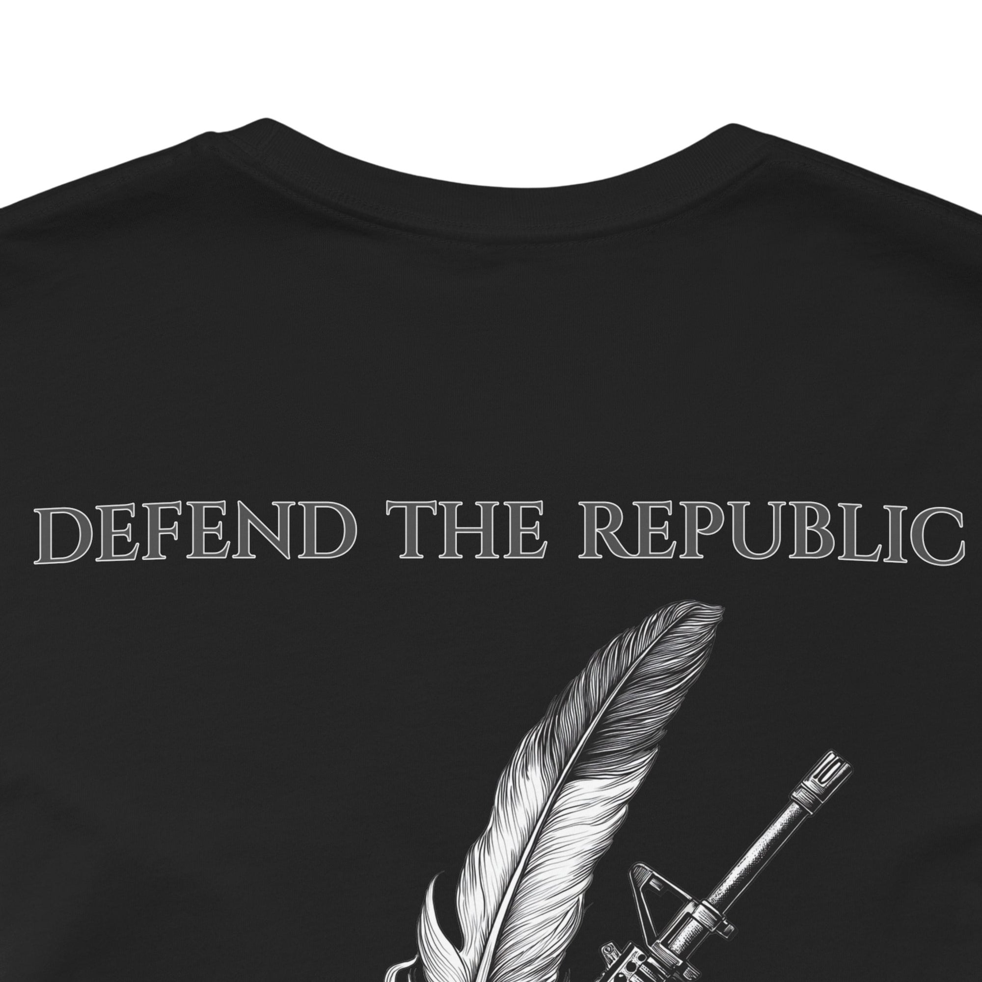 back closeup view of an black colored t-shirt with a graphic design of a rifle crossed with a quill fountain pen and an American flag ribbon, with the quote Defend the Republic by law or by force. Patriotic Shirts. logo design on front.