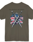 army green colored t-shirt featuring two crossed swords in front of a full-color American flag graphic, with the text "Ius Populi ad Arma" in bold black font above.