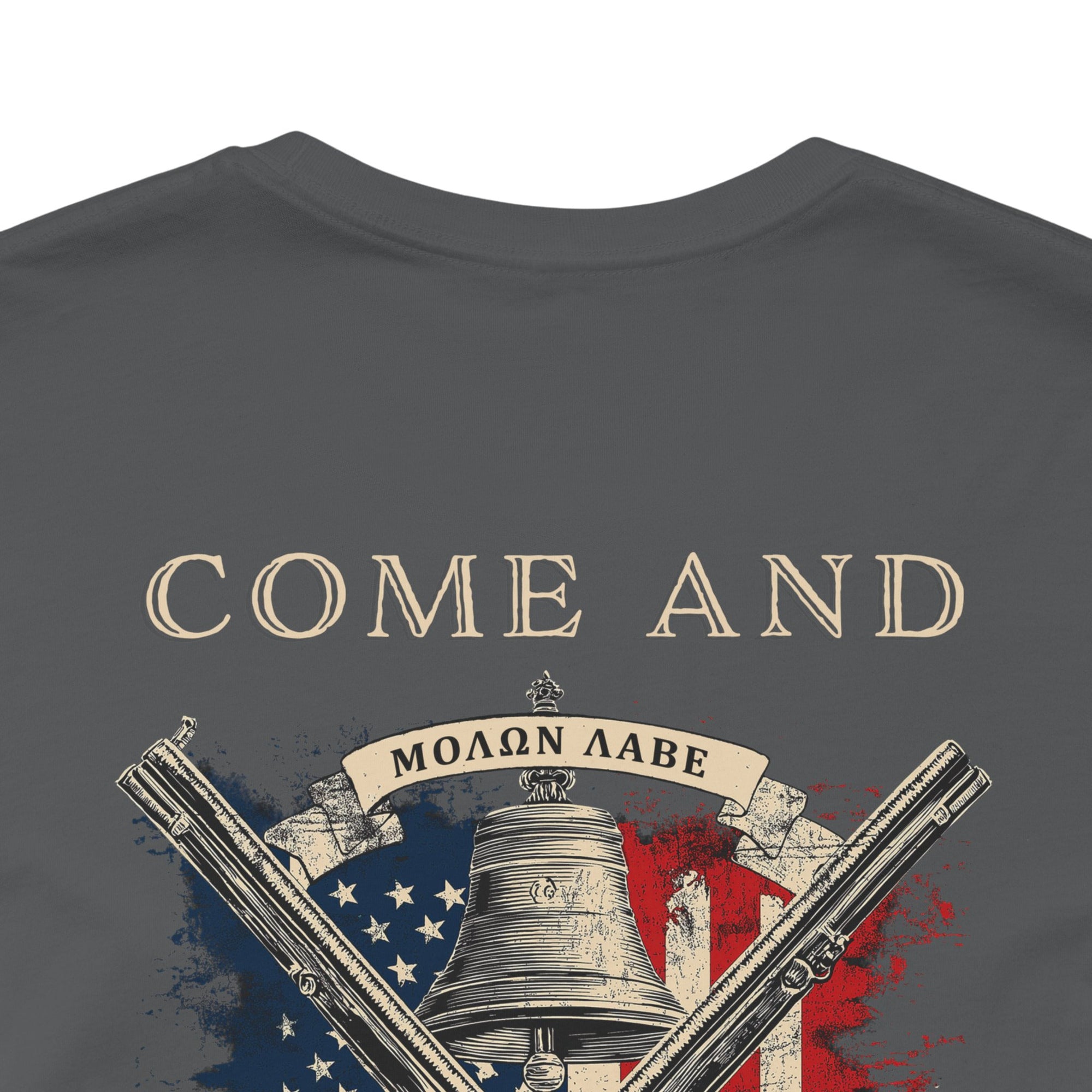 rear view close up of patriotic shirt asphalt color fabric tee with logo on front and american flag with liberty  bell and crossed rifles on back, motto that states Come and Take Them  and molon labe on scroll