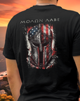 man overlooking the beach at sunset wearing a black color fabric tee with americantees.us logo on front with spartan helmet covered with american flag and motto molon labe patriotic shirt
