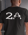 man standing in a house wearing a patriotic black colored fabric shirt with americantees.us logo on front and 2A on the back with stacked rifles forming the A