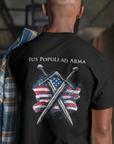 back-view-bella-canvas-tee-mockup-of-a-man-standing-in-a-dark-room-black colored t-shirt featuring two crossed swords in front of a full-color American flag graphic, with the text "Ius Populi ad Arma" in bold black font above. back view