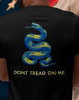 rear view of a man wearing a black colored fabric shirt with americantees.us logo on front and a Gadsden flag on the back