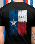 rear view of a man wearing a black colored fabric shirt standing in front of an american ribbon with americantees.us logo on front and Texas flag with rifle and Keep Texas Free writing on back