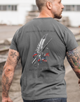 Patriotic man wearing an asphalt colored t-shirt with a graphic design of a rifle crossed with a quill fountain pen and an American flag ribbon, with the quote Defend the Republic by law or by force.