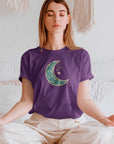 moonlit-charm-team-purple-t-shirt-crescent-moon-with-hanging-stars-mockup-of-a-woman-meditating-in-a-white-bedroom