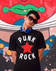 punk-rock-red-star-black-t-shirt-mockup-featuring-a-man-posing-against-a-graffiti-wall