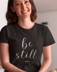 be-still-psalm-46-10-black-t-shirt-womens-christian-inspiring-happy-hispanic-woman-sitting-down-in-the-kitchen-while-wearing-a-round-neck-tee-mockup