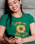 focus-on-the-good-sunflower-heather-kelly-green-t-shirt-womens-mockup-of-a-woman-sitting-on-the-stairs