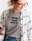 gettin-piggy-with-it-athletic-heather-grey-t-shirt-funny-dancing-pigs-mockup-featuring-a-woman-working