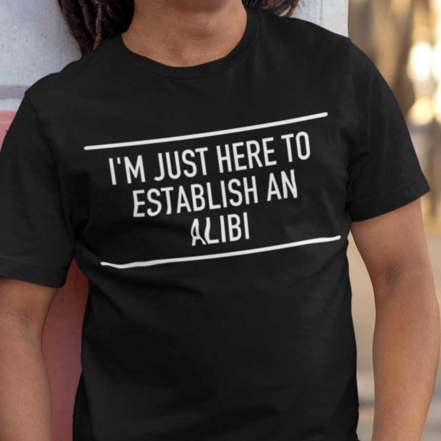 im-just-here-to-establish-an-alibi-t-shirt-bella-canvas-t-shirt-mockup-of-a-happy-man-leaning-against-a-wall