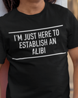 im-just-here-to-establish-an-alibi-t-shirt-bella-canvas-t-shirt-mockup-of-a-happy-man-leaning-against-a-wall