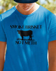 smoke-brisket-not-meth-heather-royal-blue-t-shirt-funny-cow-design-template-of-a-young-man-posing-at-a-park