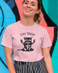 stay-trashy-with-racoon-pink-t-shirt-unisex-tee-mockup-of-a-smiling-girl-in-front-of-a-wall-with-colorful-illustrations