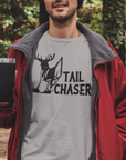 tail-chaser-athletic-heather-grey-t-shirt-mockup-featuring-a-man-holding-a-20-oz-travel-mug-in-the-woods