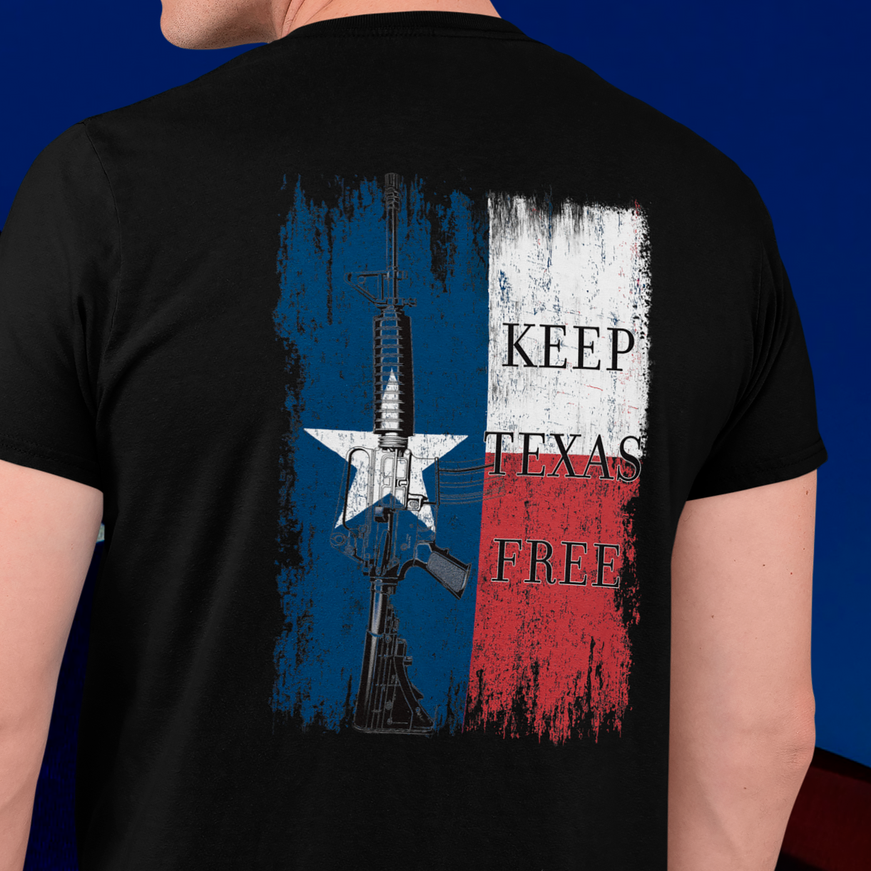 rear view of a man wearing a  black colored fabric shirt standing in front of an american flag with americantees.us logo on front and Texas flag with rifle and Keep Texas Free writing on back 