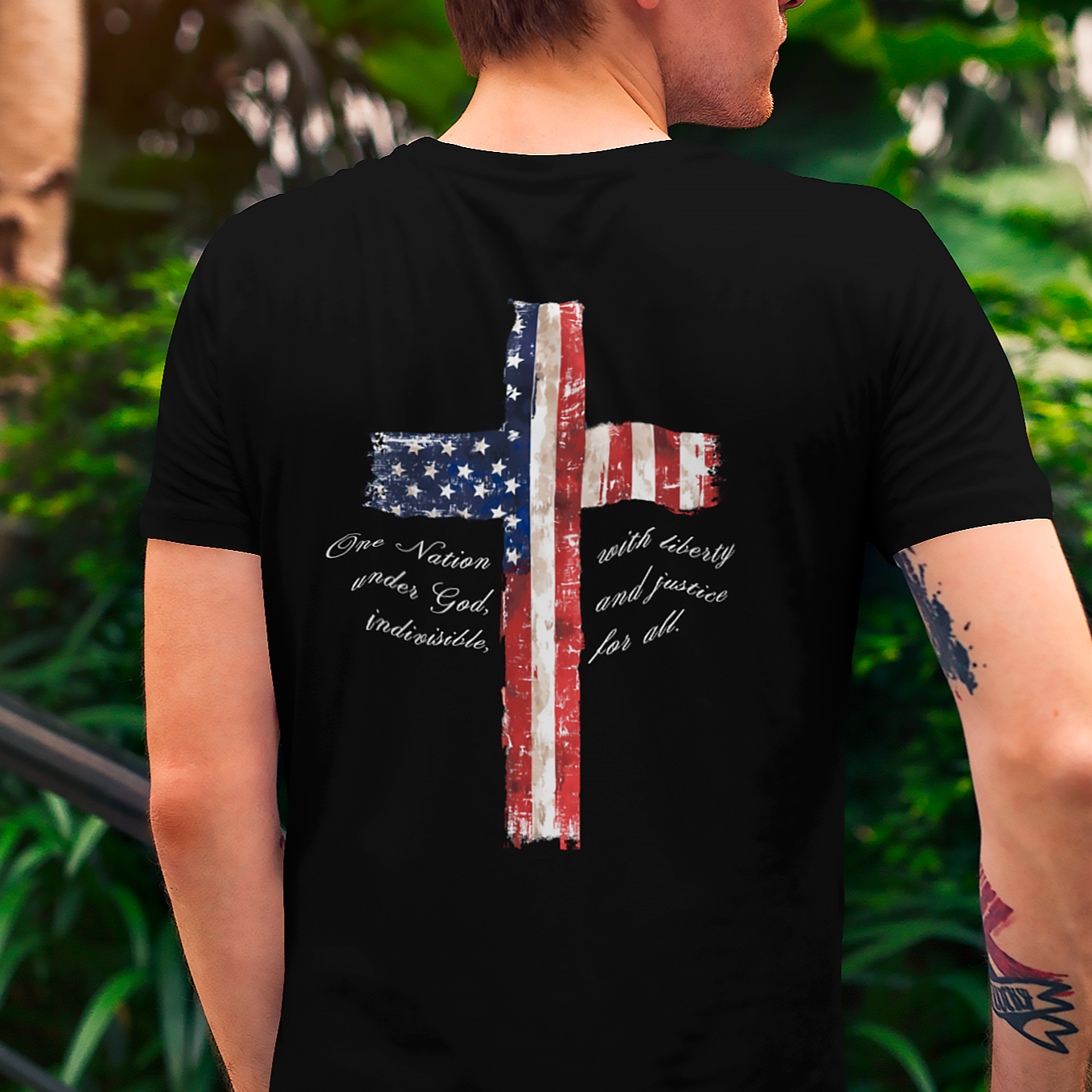 rear view of a man wearing a black colored fabric patriotic shirt with American flag in shape of a Christian cross with pledge of allegiance surrounding image