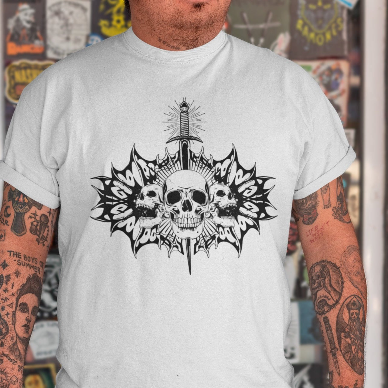 blade-and-bone-punk-rock-asphalt-t-shirt-mockup-of-a-man-with-tattooed-arms-posing-by-a-glass-door