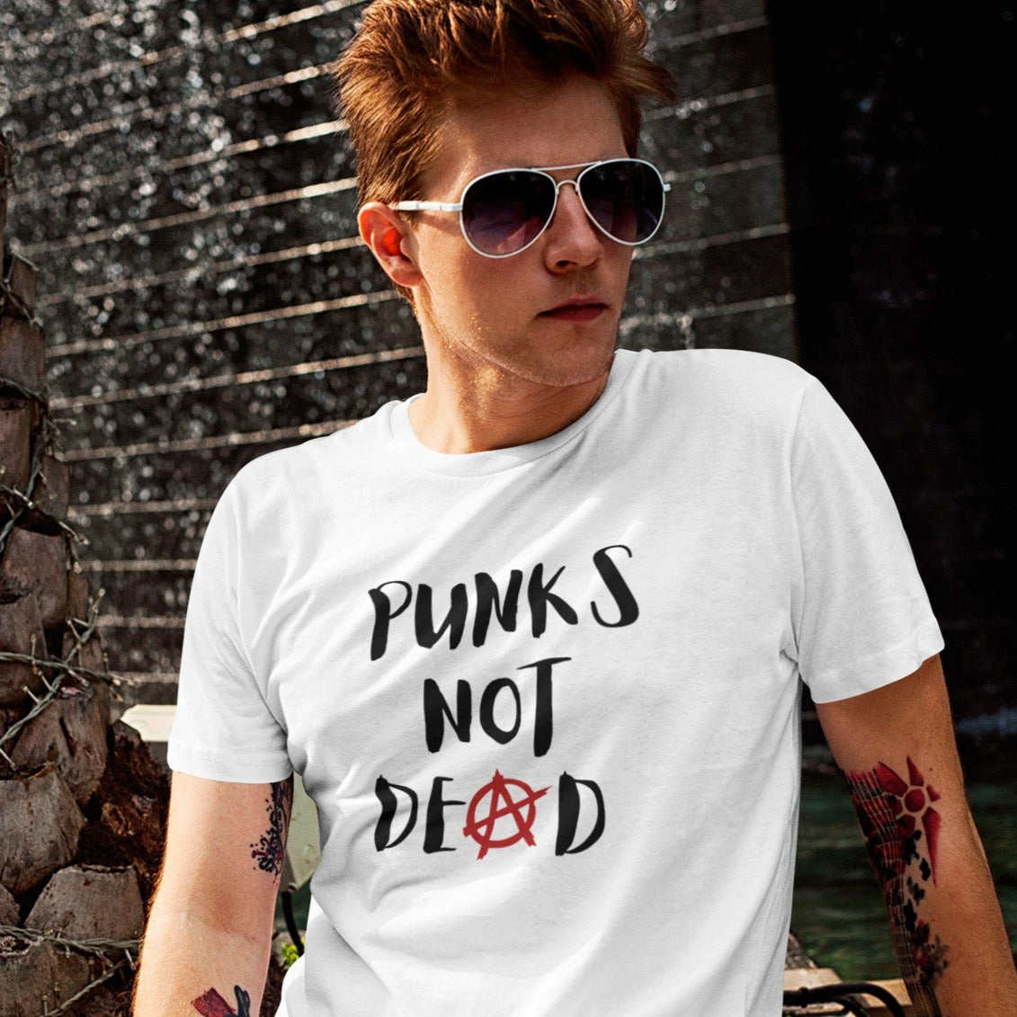 punks-not-dead-anarchy-sign-white-t-shirt-mockup-of-a-red-haired-man-posing-next-to-a-fountain