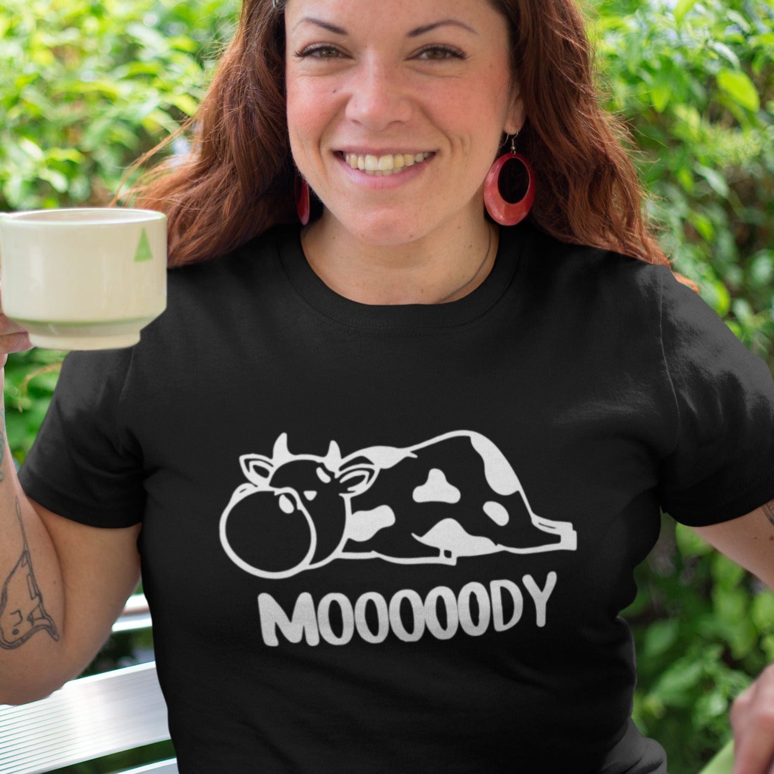 Mooooody-cow-farm-black-t-shirt-funny-mockup-of-a-happy-middle-aged-woman-wearing-a-tee-while-having-a-coffee-in-the-backyard