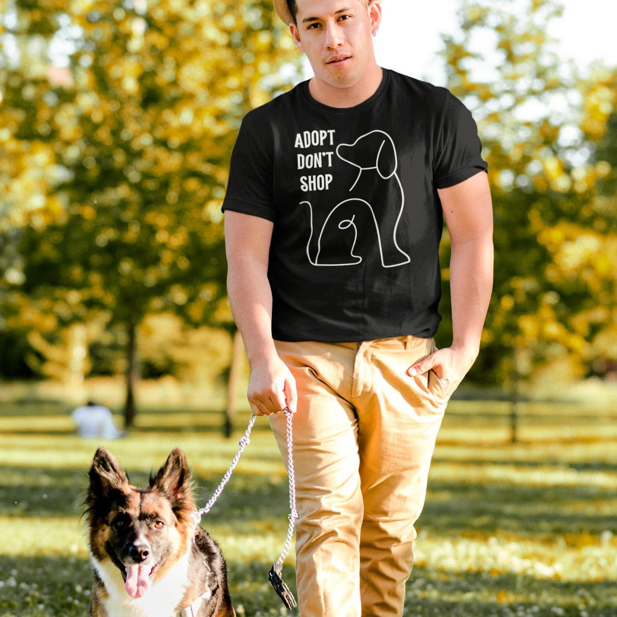 adopt-dont-shop-black-t-shirt-with-dog-graphic-unisex-mockup-of-a-man-walking-his-dog-at-a-park