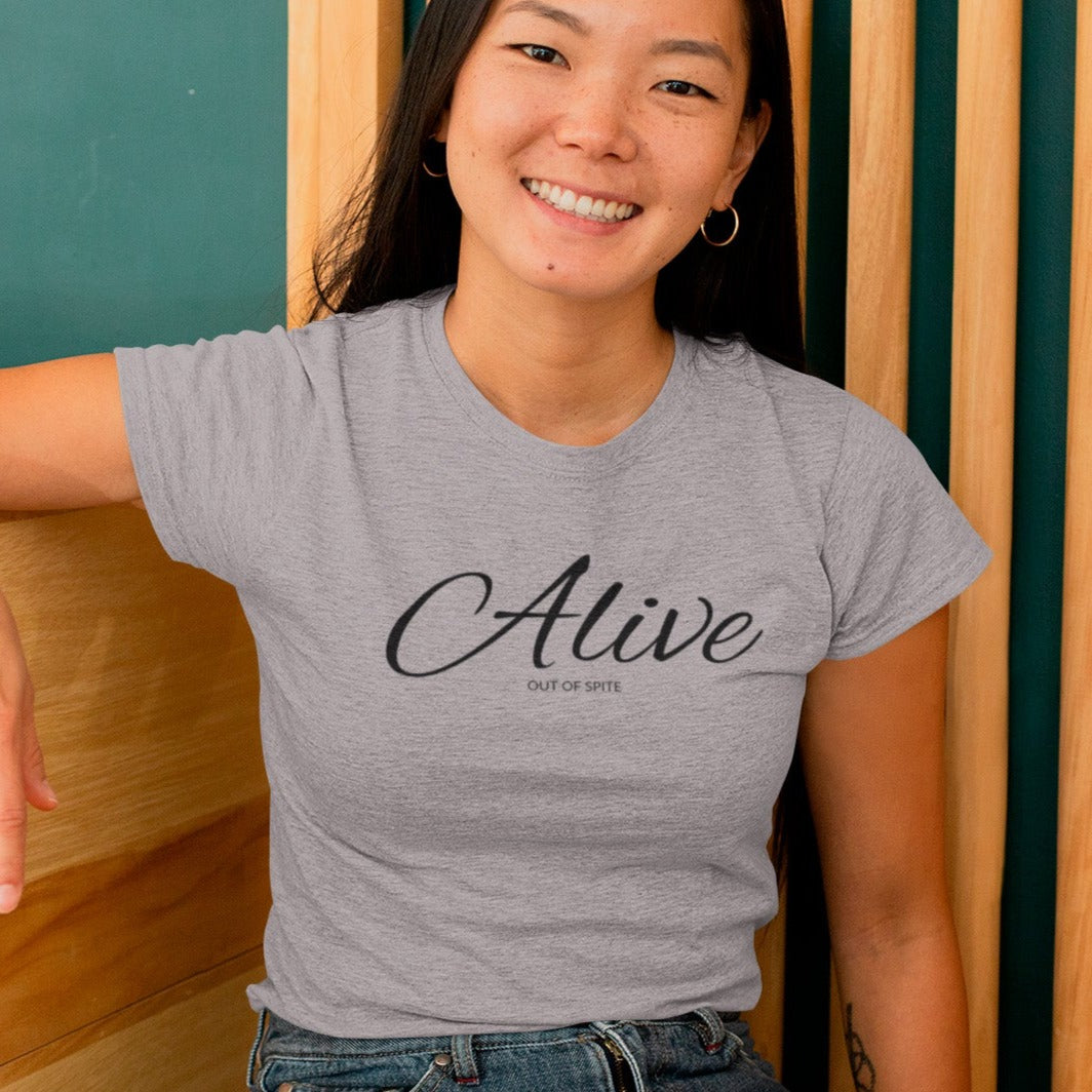 alive-out-of-spite-athletic-heather-grey-t-shirt-funny-mockup-of-a-woman-with-a-heather-tee-sitting-against-a-wooden-background
