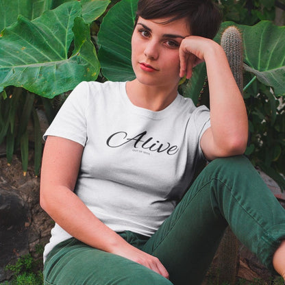 alive-out-of-spite-white-t-shirt-funny-mockup-of-a-girl-relaxing-near-cactus-and-plants-wearing-a-tee