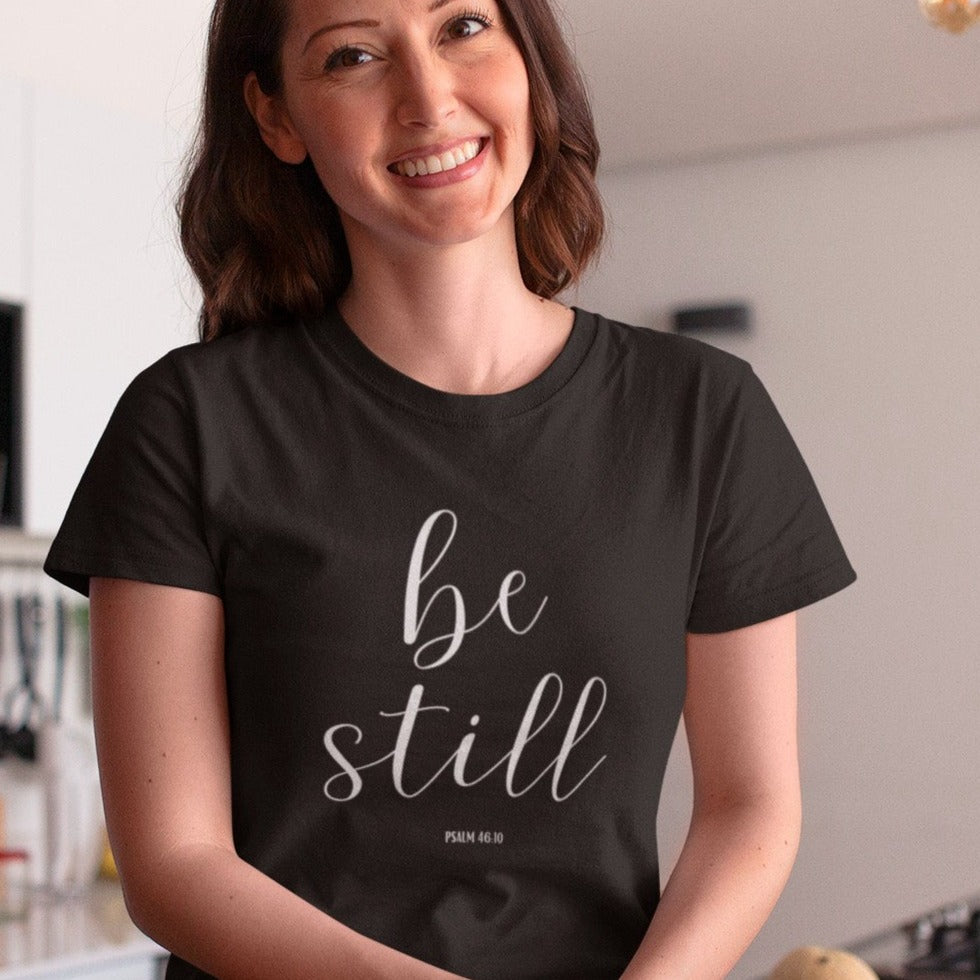 be-still-psalm-46-10-black-t-shirt-womens-christian-inspiring-happy-hispanic-woman-sitting-down-in-the-kitchen-while-wearing-a-round-neck-tee-mockup