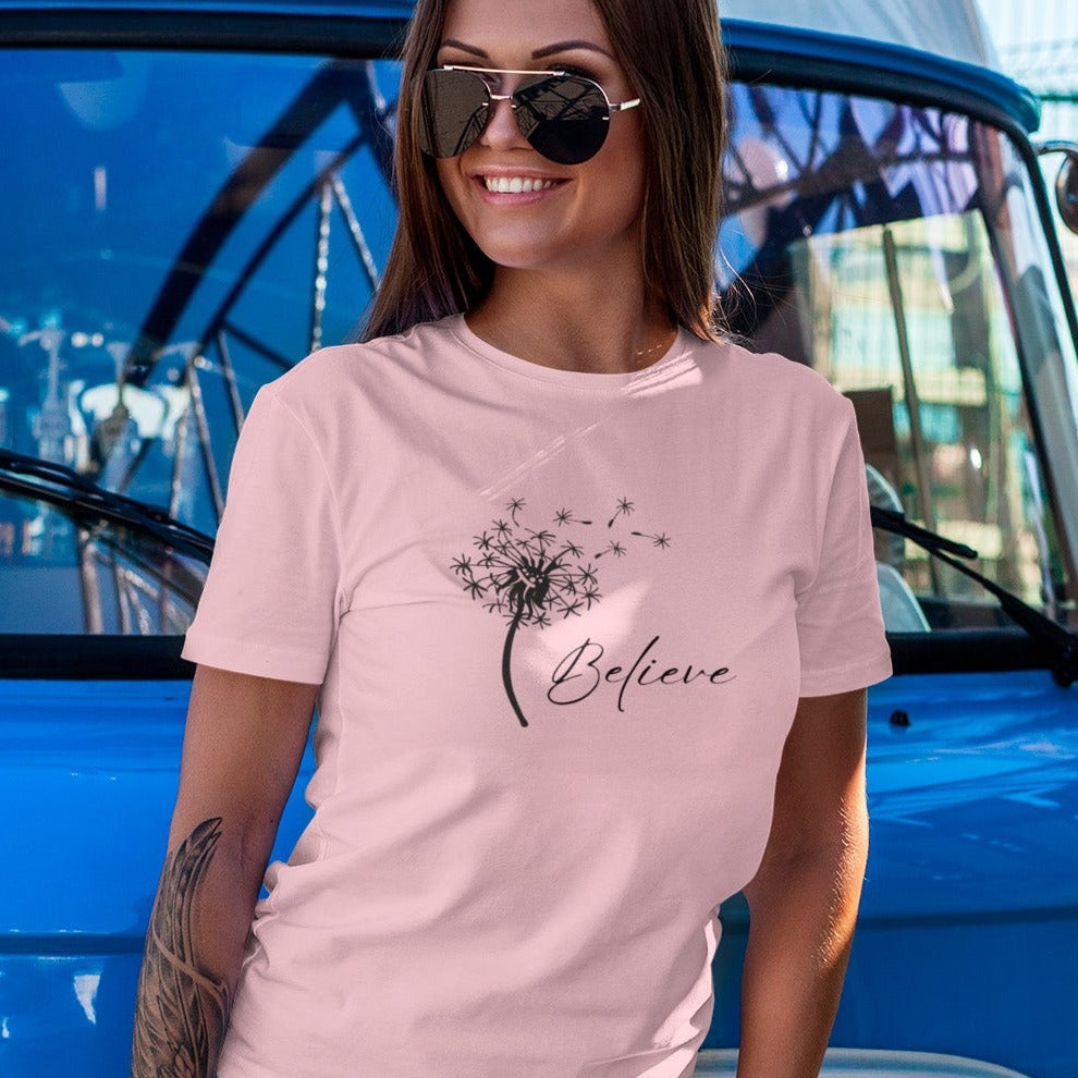 believe-with-dandelion-wishes-pink-t-shirt-womens-inspiring-mockup-featuring-a-woman-leaning-on-a-van