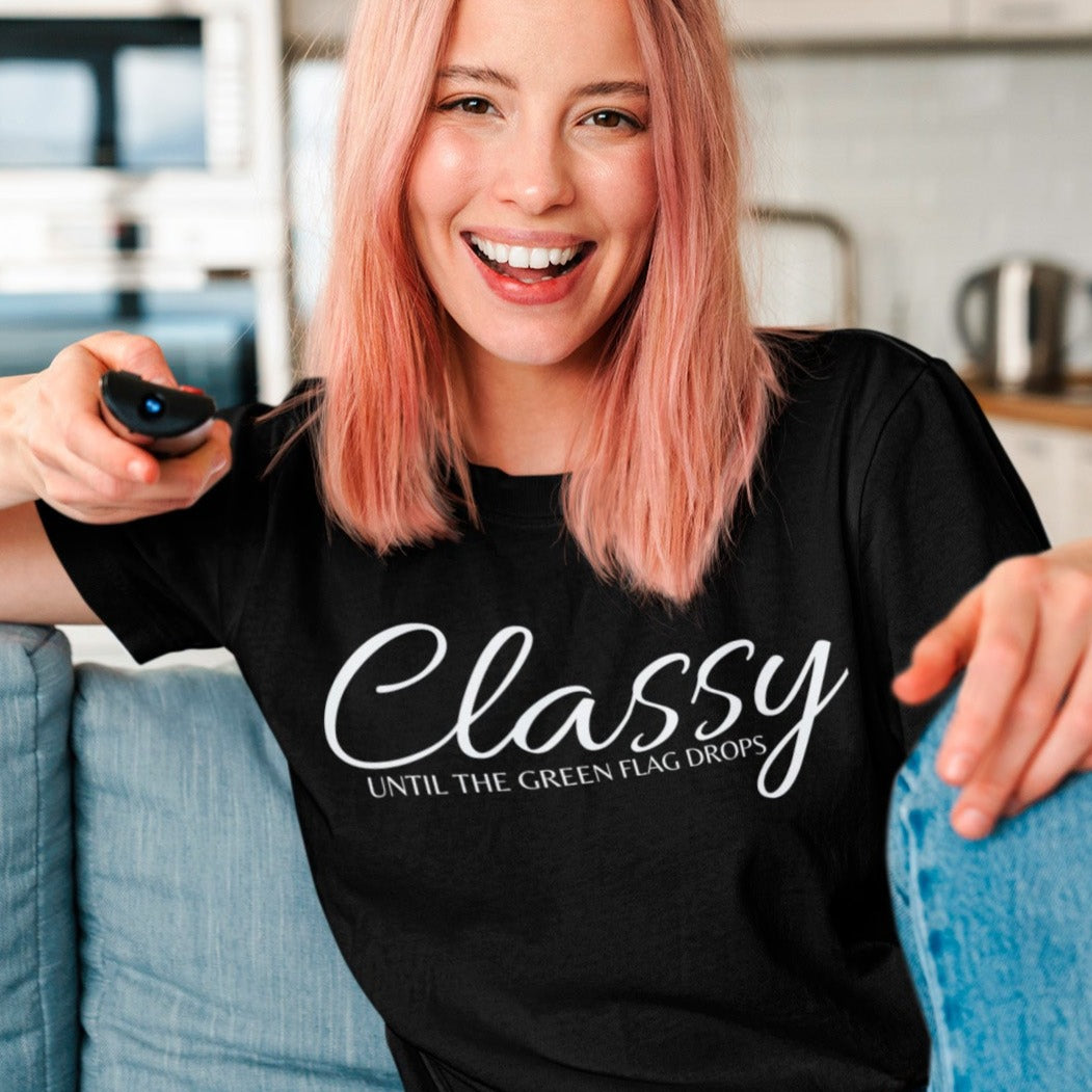 classy-until-the-green-flag-drops-black-t-shirt-racing-womens-mockup-of-a-woman-with-a-unisex-tee-holding-a-tv-remote