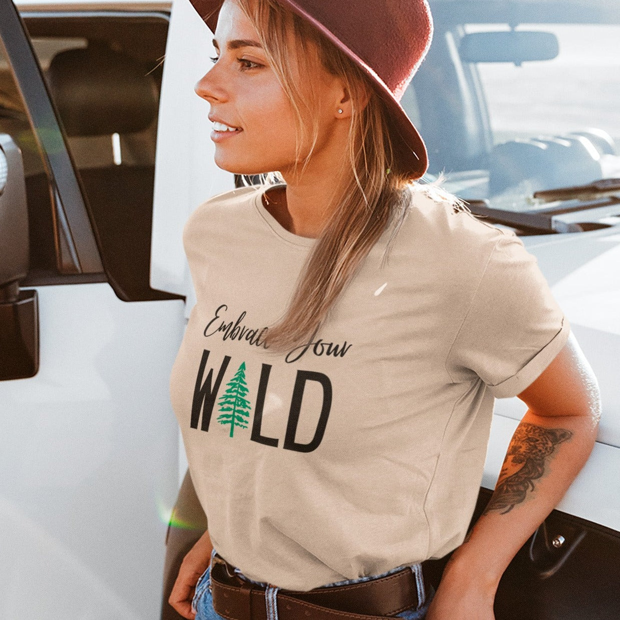 embrace-your-wild-with-tree-graphic-soft-cream-t-shirt-womens-outdoorsmockup-featuring-a-stylish-woman-with-a-tattoo