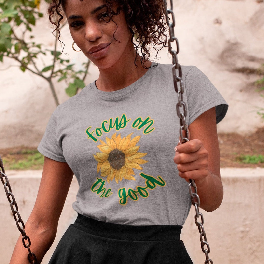 focus-on-the-good-sunflower-athletic-heather-grey-t-shirt-womens-mockup-of-a-heathered-tee-of-a-woman-on-a-swing