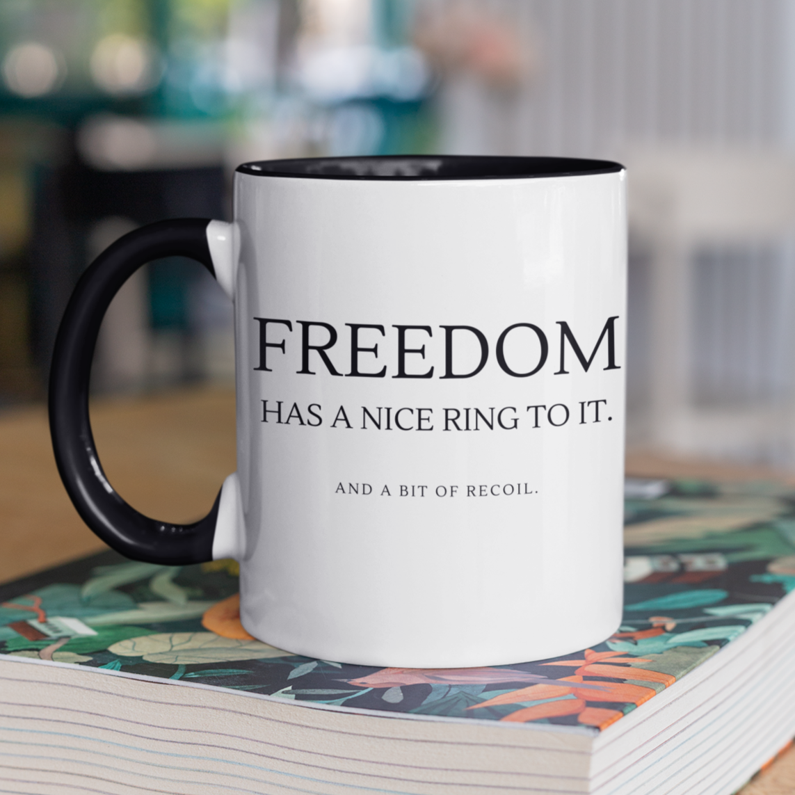 freedom-has-a-nice-ring-to-it-and-a-bit-of-recoil-glossy-mug-11-oz-2a-mockup-of-a-two-toned-coffee-mug-mockup-on-a-table