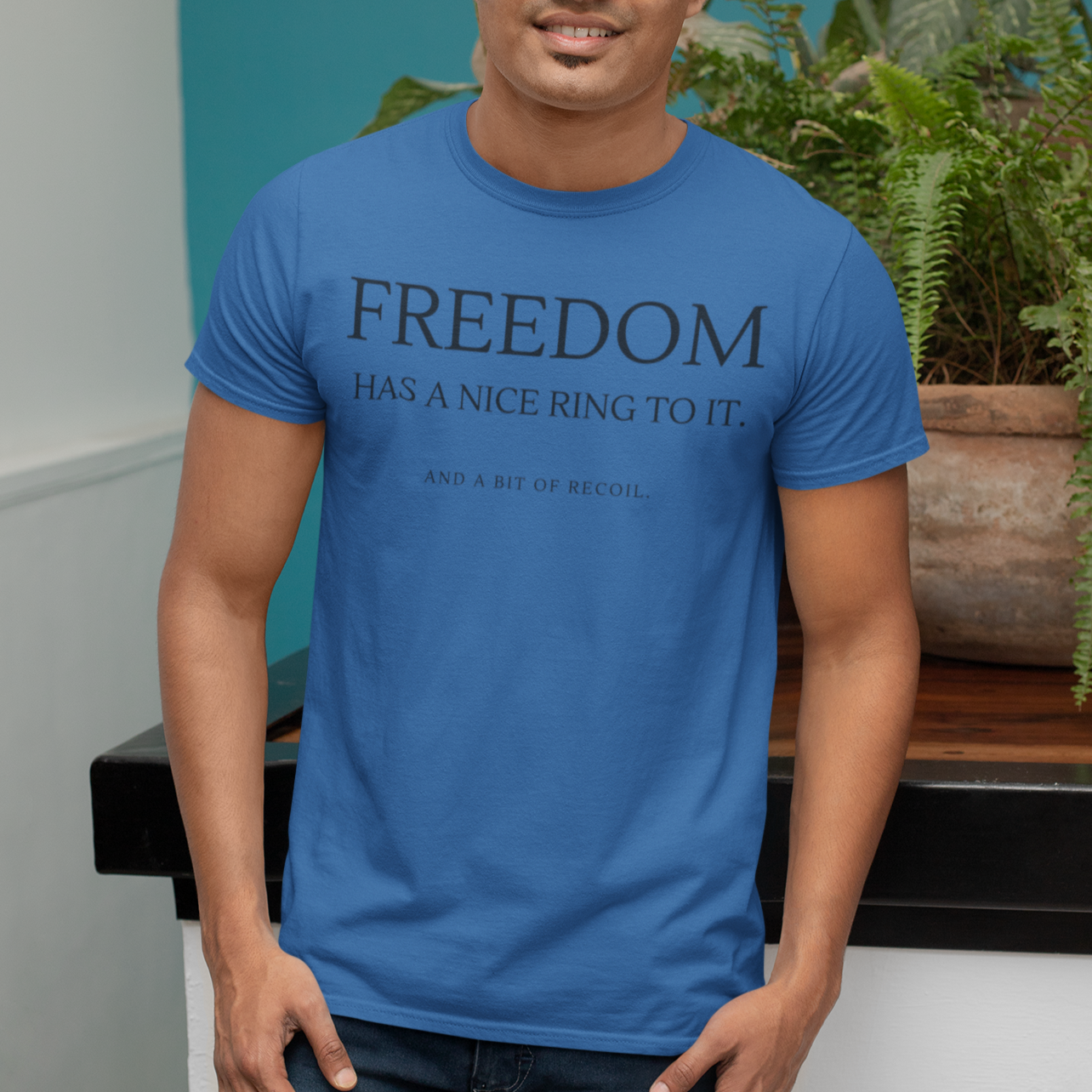 freedom-has-a-nice-ring-to-it-and-a-bit-of-recoil-true-royal-blue-t-shirt-2a-mockup-of-a-man-with-a-tee-posing-next-to-a-plant