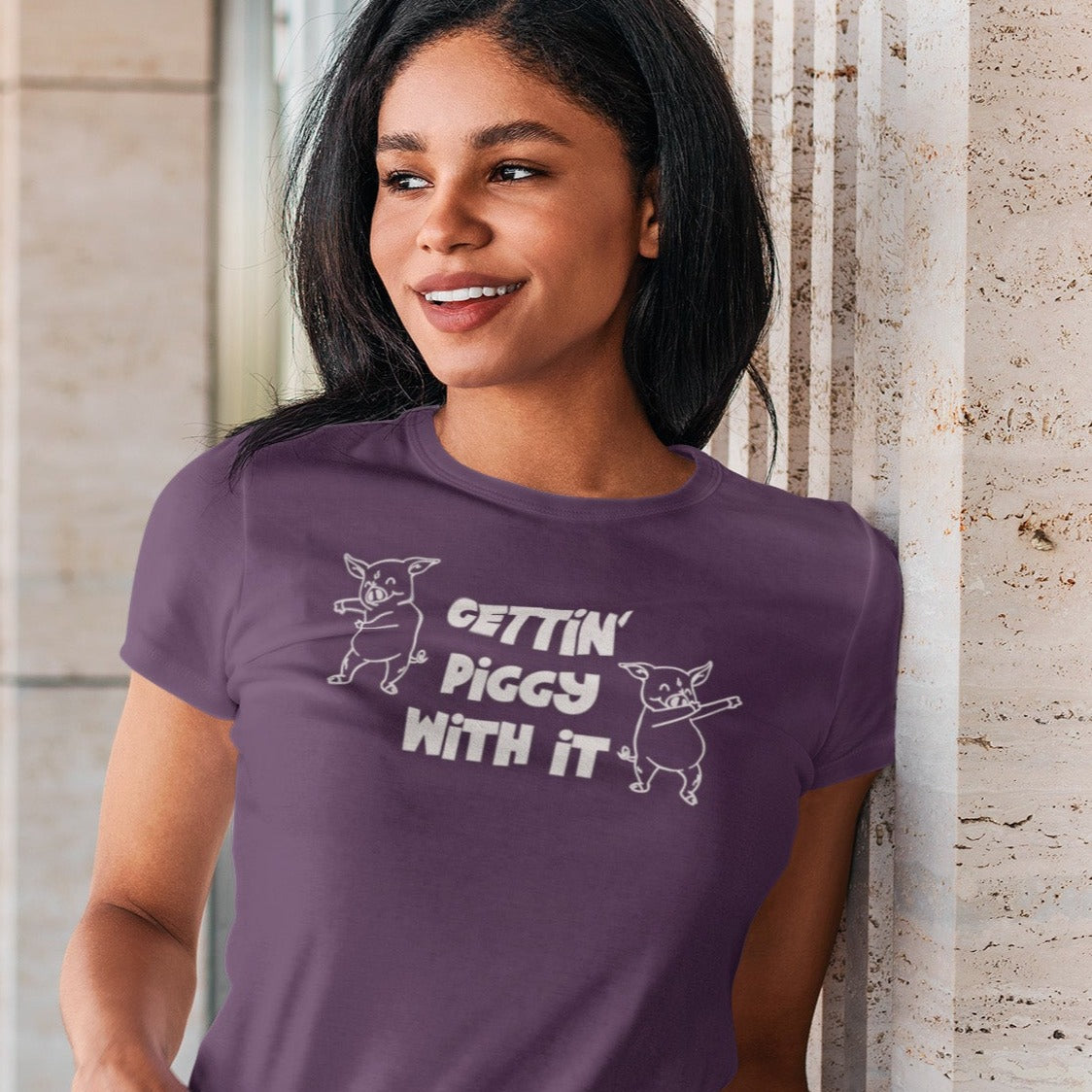 gettin-piggy-with-it-team-purple-t-shirt-funny-dancing-pigs-mockup-of-a-woman-wearing-a-t-shirt-and-leaning-against-a-granite-wall