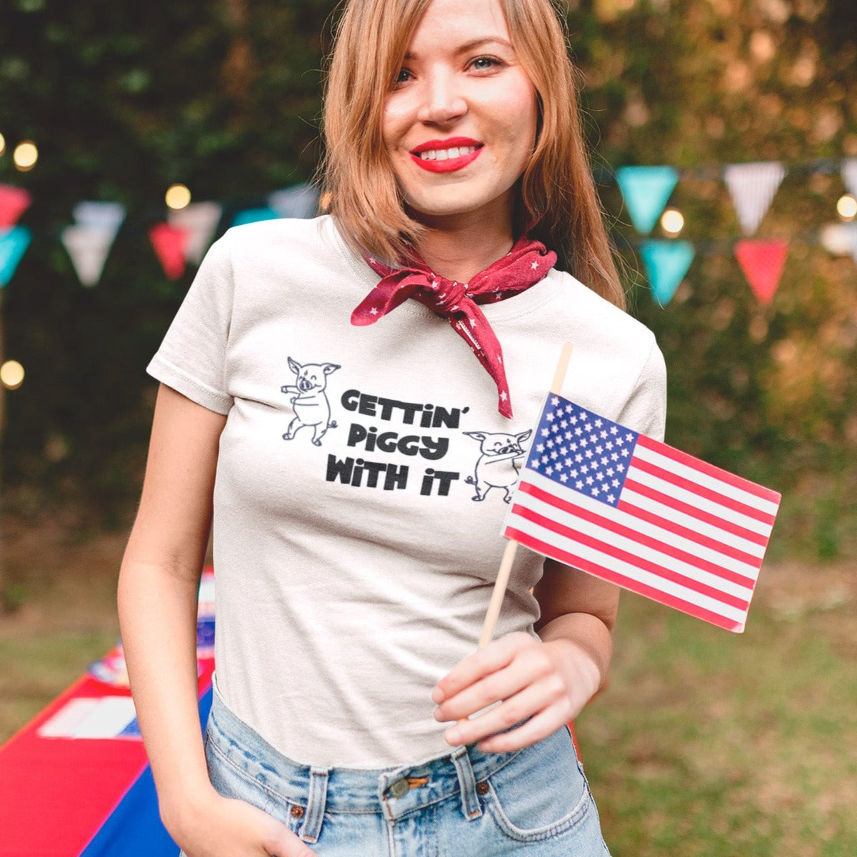 gettin-piggy-with-it-white-t-shirt-funny-dancing-pigs-smiling-patriot-girl-wearing-a-t-shirt-mockup-at-a-4th-of-july-bbq-party