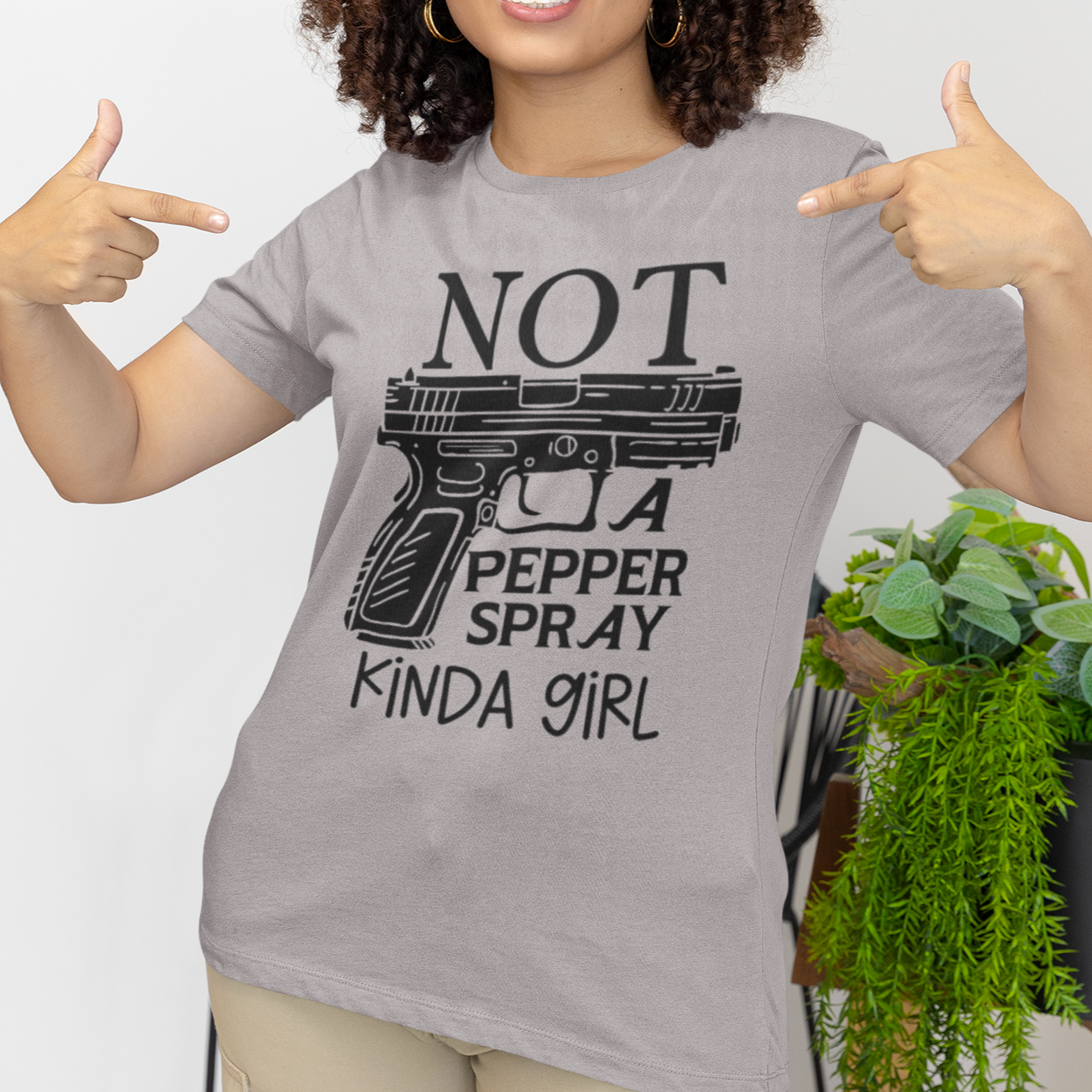 gun-girl-not-a-pepper-spray-kind-of-girl-athletic-heather-grey-t-shirt-mockup-featuring-a-woman-pointing-at-her-bella-canvas-tee