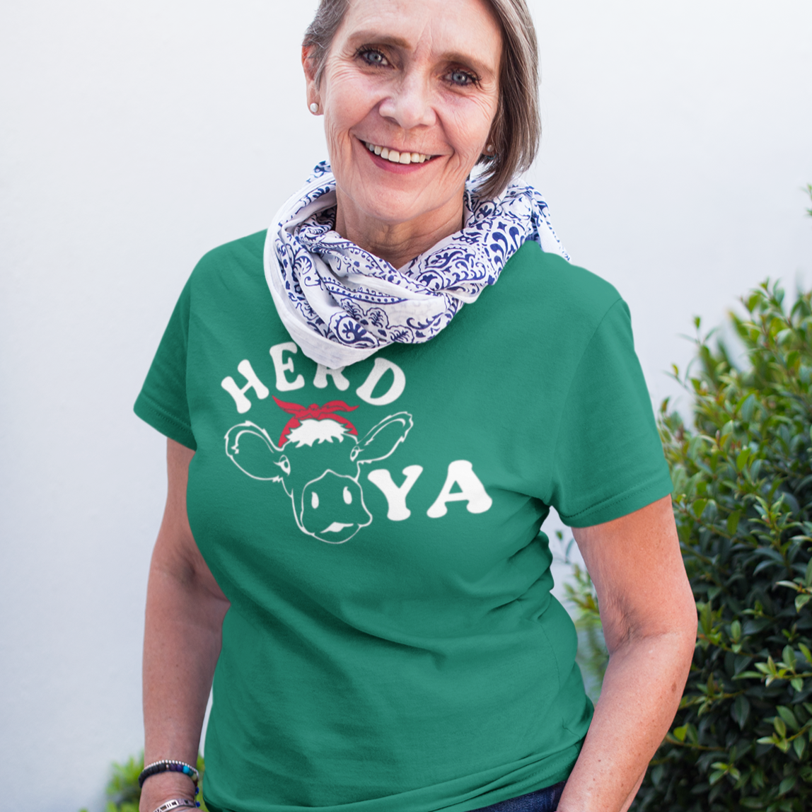 herd-ya-heather-kelly-green-t-shirt-cowgirl-senior-woman-wearing-a-round-neck-tee-mockup-against-plants