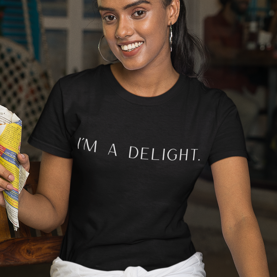 im-a-delight-white-t-shirt-womens-funny-sarcastic-mockup-of-a-smiling-woman-posing-with-an-indian-snack
